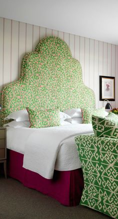 a green and white headboard in a bedroom next to a bed with two chairs