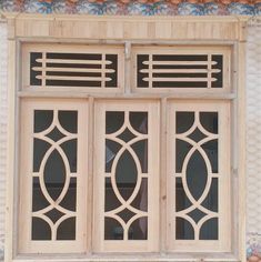 an old window with decorative iron work on the outside and side panels, in front of a stucco wall