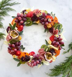 a wreath made out of fruits and vegetables on a marble surface with greenery around it