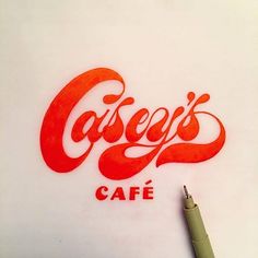 a drawing of the word cafe is shown on a piece of paper next to a pen