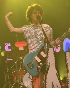 a man standing on top of a stage holding a guitar