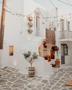 an alleyway with potted plants and decorations on the wall, in front of a white building