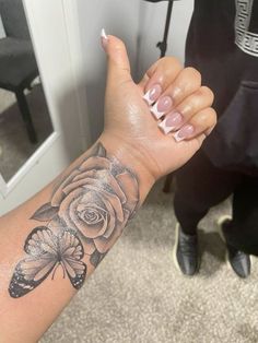 a woman's arm with a butterfly and rose tattoo on it