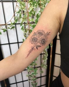 a woman with a tattoo on her arm holding a bouquet of sunflowers and a knife