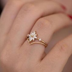 a woman's hand wearing a gold ring with flowers on the middle and side