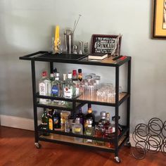 a bar cart filled with liquor bottles on top of a hard wood floor