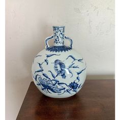 a blue and white vase sitting on top of a wooden table