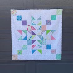 a quilted wall hanging on the side of a garage door with an arrow design