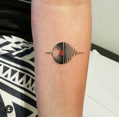 a person with a tattoo on their arm has a vinyl record in the shape of a heart