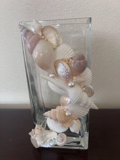 a glass vase with seashells and pearls in it