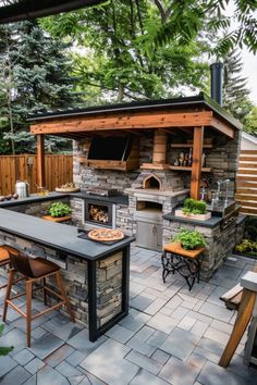 an outdoor kitchen with stone counter tops and grilling area in the middle of it