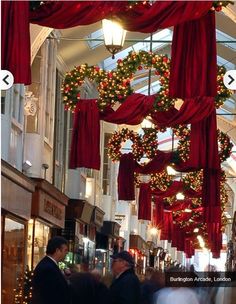 people are walking through an indoor mall decorated for christmas