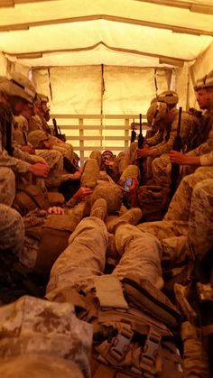 some soldiers are sitting on the floor with their cell phones in hand and looking at them