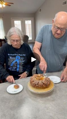 an older man and woman standing at a kitchen counter cutting a cake with a knife