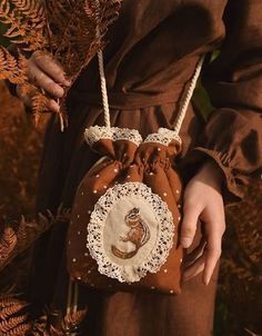 a woman is holding a brown purse with a cat on it's back and lace around the bottom