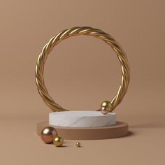 a gold and white marble ring with two balls on the base, in front of a beige background