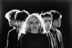 blond haired woman standing in front of four young men