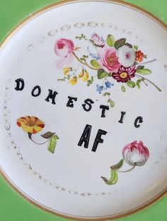 a white plate with flowers on it that says domestic af