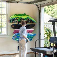 a woman standing in front of a wall mounted surfboard rack with two boards on it