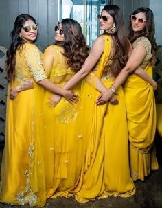 four women in yellow dresses posing for the camera with their hands on their hipss