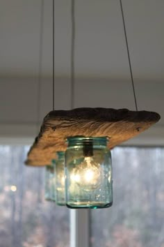 a mason jar hanging from a light fixture in front of a window with trees outside