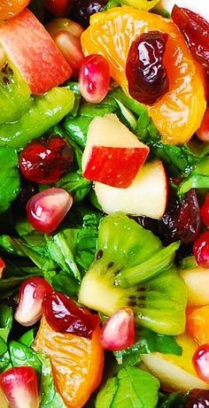 a salad with spinach, apples, oranges and cranberries