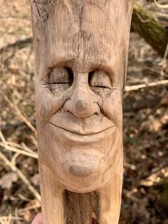 a wooden statue with a smiling face on it's head is held up to the camera