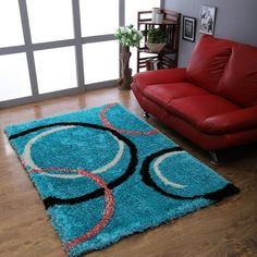 a living room with a red couch and blue rug on the wooden floor next to a window