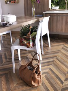 a brown bag sitting on top of a wooden floor next to a white dining room table