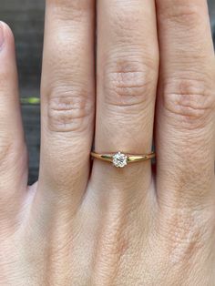 a woman's hand with a diamond ring on top of her finger and the other hand holding an engagement ring