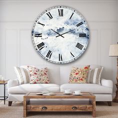 a large clock mounted to the side of a wall above a white couch in a living room