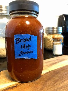 a glass jar filled with sauce sitting on top of a wooden table