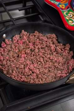 a frying pan filled with meat sitting on top of an oven