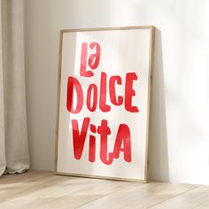 a red and white poster with the words la dolce vita on it in front of a window