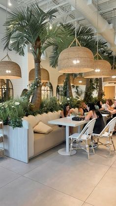 people sitting at tables in a restaurant with palm trees