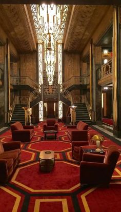 an elegant lobby with red carpet and gold trim on the walls, chandelier and stairs