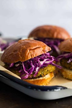 two burgers sitting on top of a tray with coleslaw