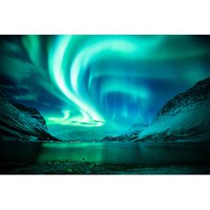 an aurora bore is seen in the sky over water and mountains, with snow on the ground