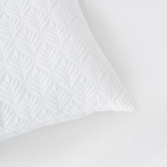 a white pillow on top of a white bed