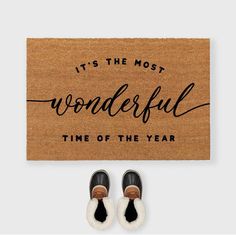 a door mat that says it's the most wonderful time of the year with two pairs of shoes next to it