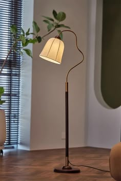 a lamp that is on top of a wooden floor next to a potted plant