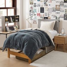 a bed sitting in a bedroom next to a wooden desk and window with lots of pictures on the wall