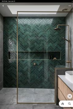 a bathroom with green tiles on the walls and floor, along with a walk in shower