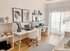 a white desk with two laptops on top of it next to a chair and window