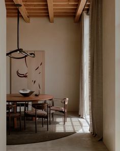 a dining room table and chairs in front of a large window with wooden beams on the ceiling