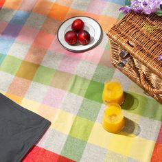 two glasses of orange juice sit on a table next to an empty plate and basket