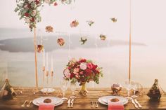 a wooden table topped with plates and flowers