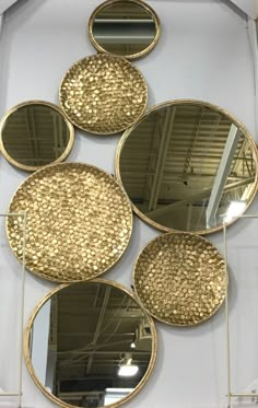 four circular mirrors hanging on the wall in front of a white wall with gold circles