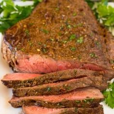 a piece of roast beef on a white plate with parsley sprinkled around it