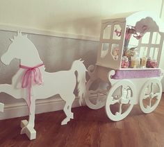 a toy horse drawn carriage next to a wall with candy in it's display case